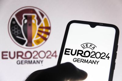 Uma mão segurando um celular com a logo da Euro Copa 2024 na tela
