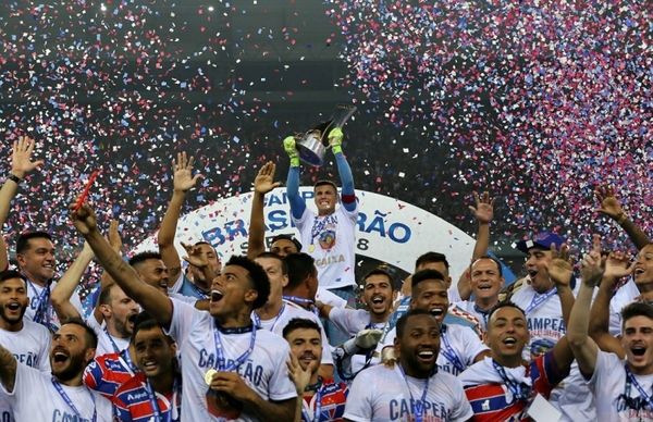 a group of men holding a trophy in front of a crowd