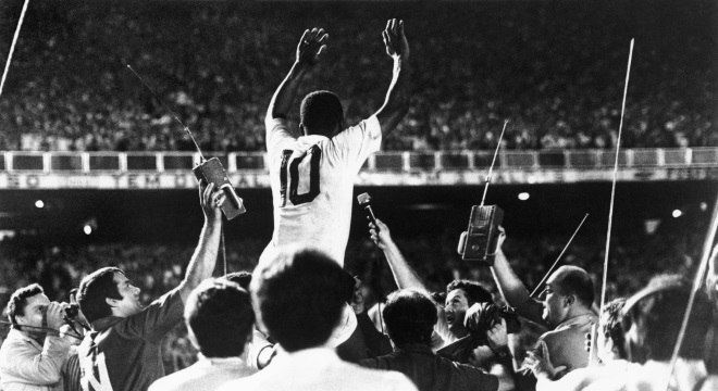 a black and white photo of a man holding a trophy in front of a crowd
