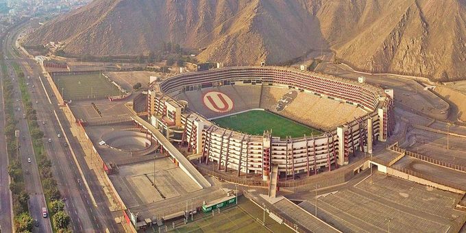 an aerial view of a stadium with mountains in the background