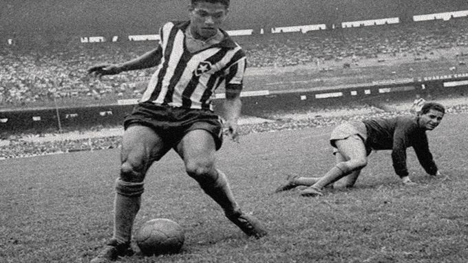 a black and white photo of a man kicking a soccer ball