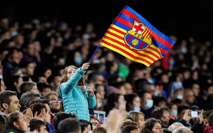 Um garoto segurando a bandeira do Barcelona.