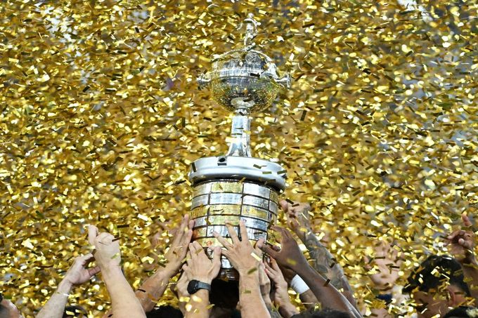 a mãos de jogadores levantando a taça da Copa Libertadores da América