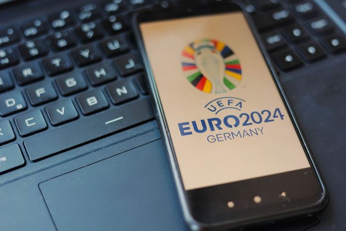 Um telefone celular, com a logo da Euro Copa 2024, sobre o teclado de um laptop