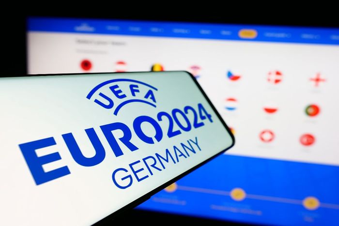 A tela de uma celular com o logo da Euro Copa 2024 em frente a tela de um computador