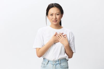 Woman in white T-shirt pressing against her chest with both hands