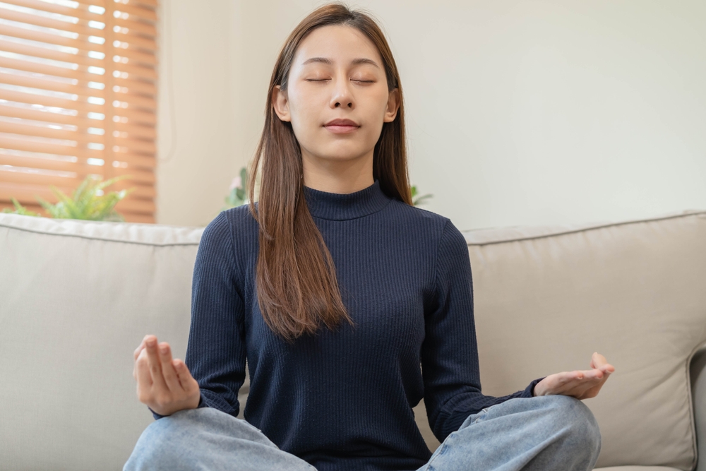 A young woman sitting with her legs crossed and meditating 