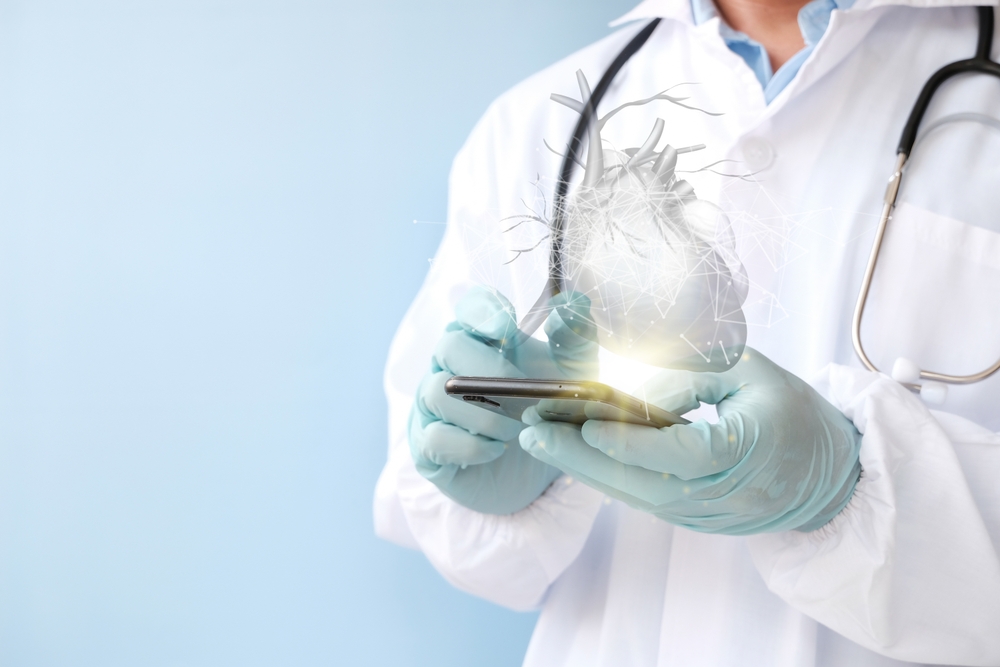 Doctor in lab coat using smartphone to check virtual Heart