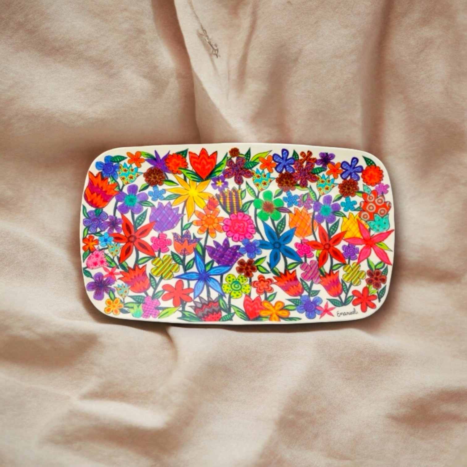 a plate with flowers painted on it sitting on a bed