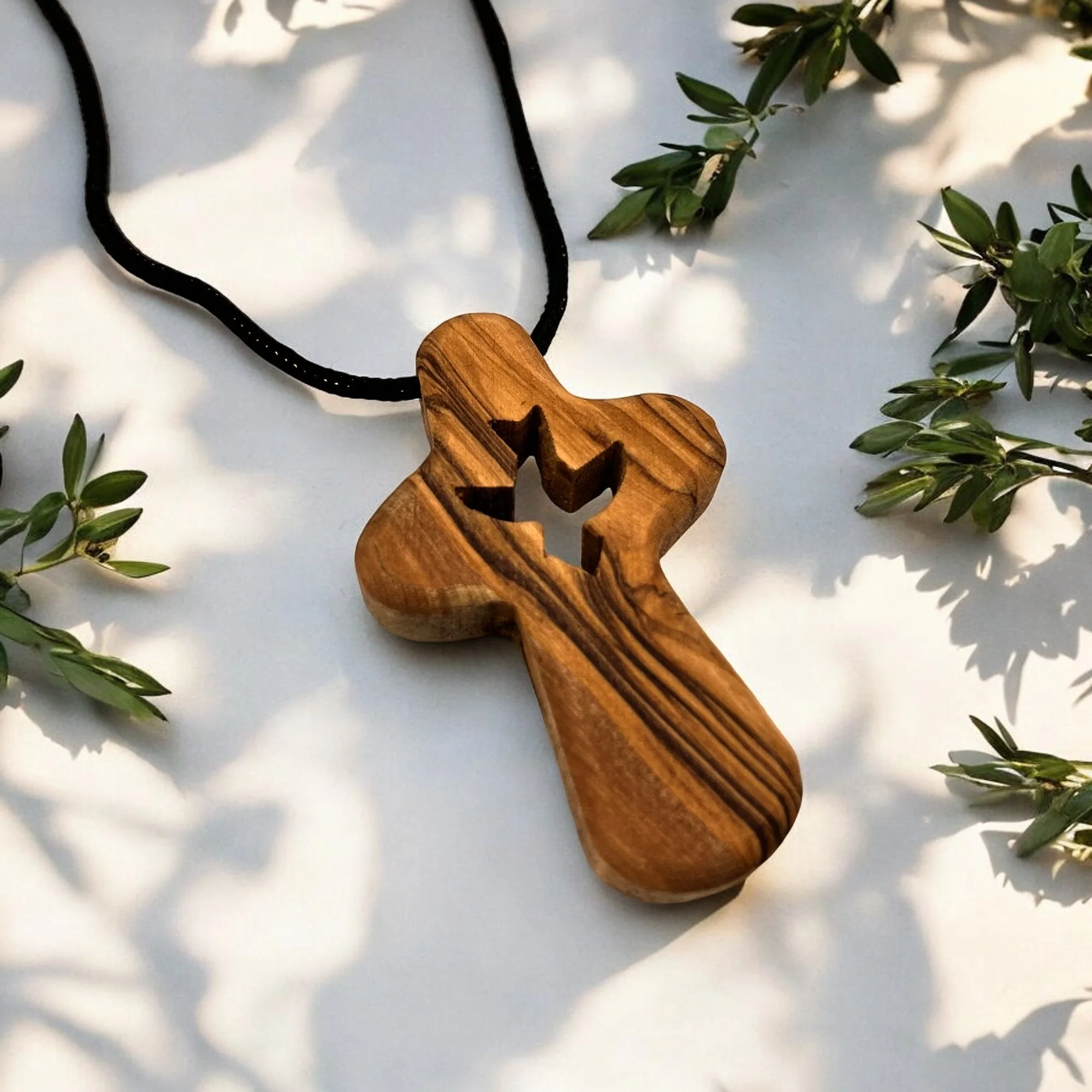 a wooden cross on a black cord on a white surface