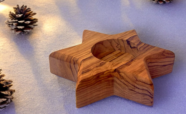 a wooden object sitting on top of a table next to pine cones