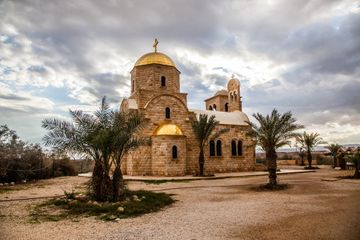 Baptist church with gold roof and cross surrounded by palm trees