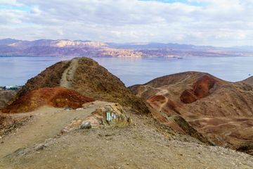 Mountain peaks with a trail running through and ocean behind