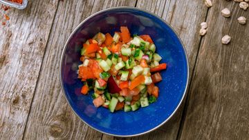 a blue bowl filled with vegetables on top of a wooden table