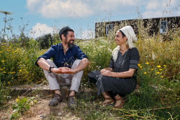 a man and a woman sitting in a field of flowers