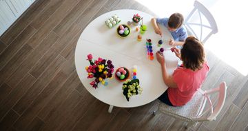 Mother and son painting eggs on white table