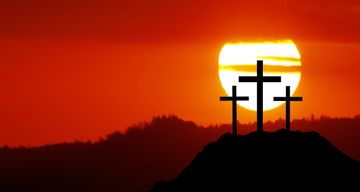 3 crosses on raised ground against a red sunset