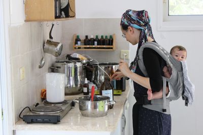 a woman holding a baby in a sling in a kitchen