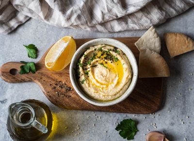 a bowl of Israeli hummus next to a glass of wine