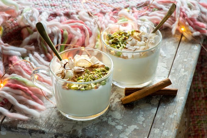 Two glasses of Sachlav topped with coconut shavings and pistachios  