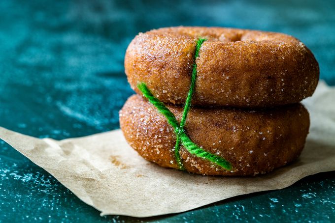 Two deep fried donuts tied together with a piece of green string