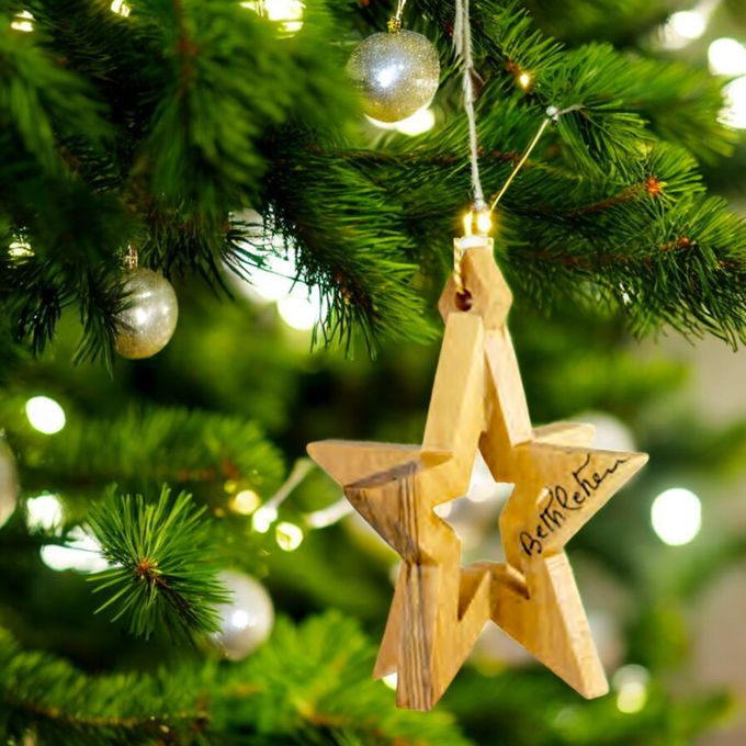 a wooden star ornament hanging from a christmas tree