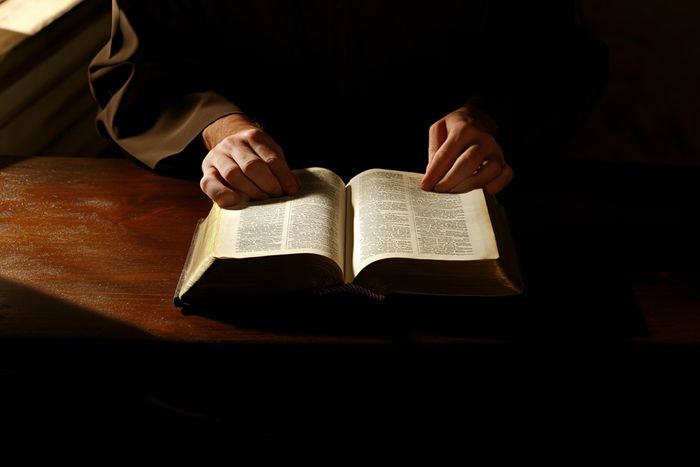 A person sitting at a table with an open Bible.