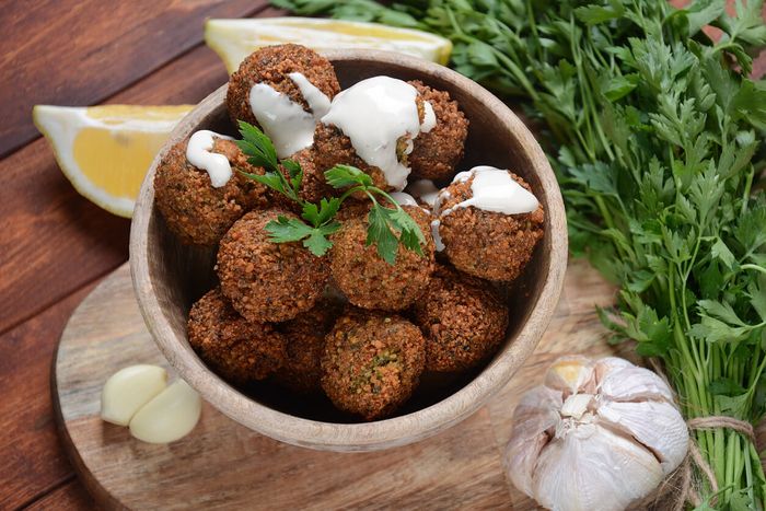 a wooden bowl filled with falafel next to a lemon wedge