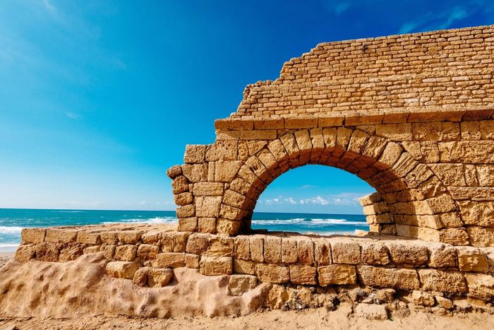 a stone arch on the beach with the ocean in the background