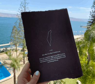 a person holding up a book with a view of the ocean