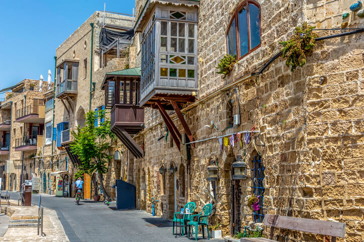 a narrow street with stone buildings and tables and chairs