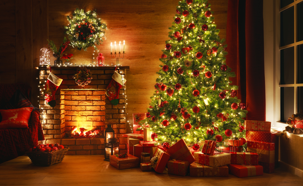 A lit-up Christmas tree next to a fireplace