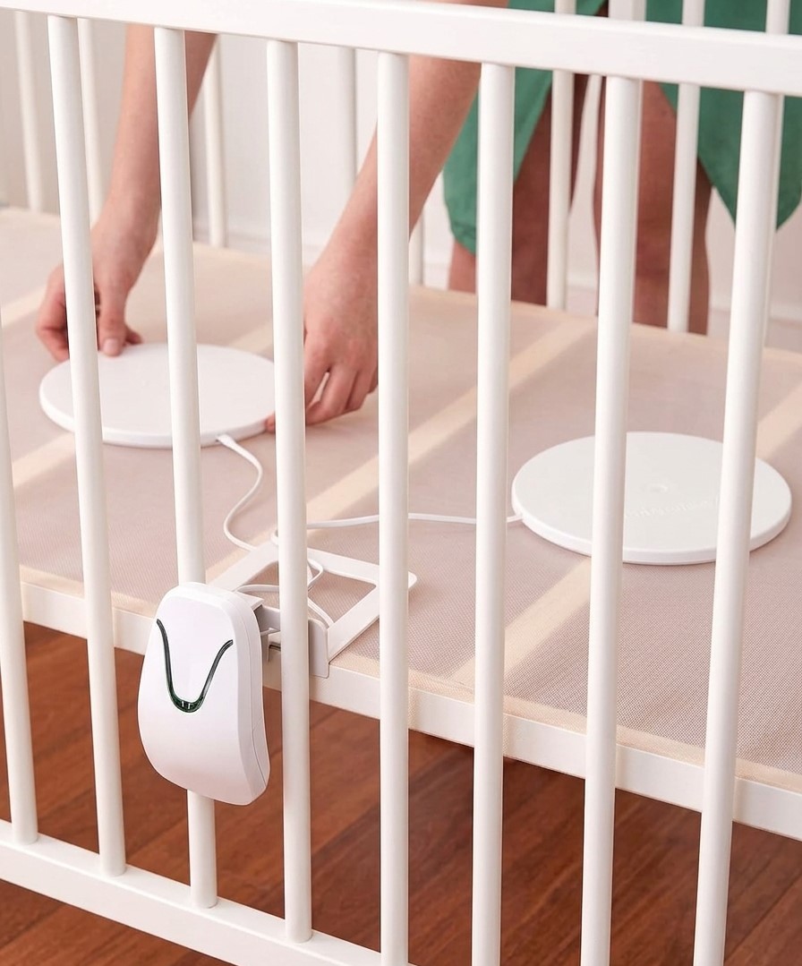 a person placing a baby breathing monitor in a crib
