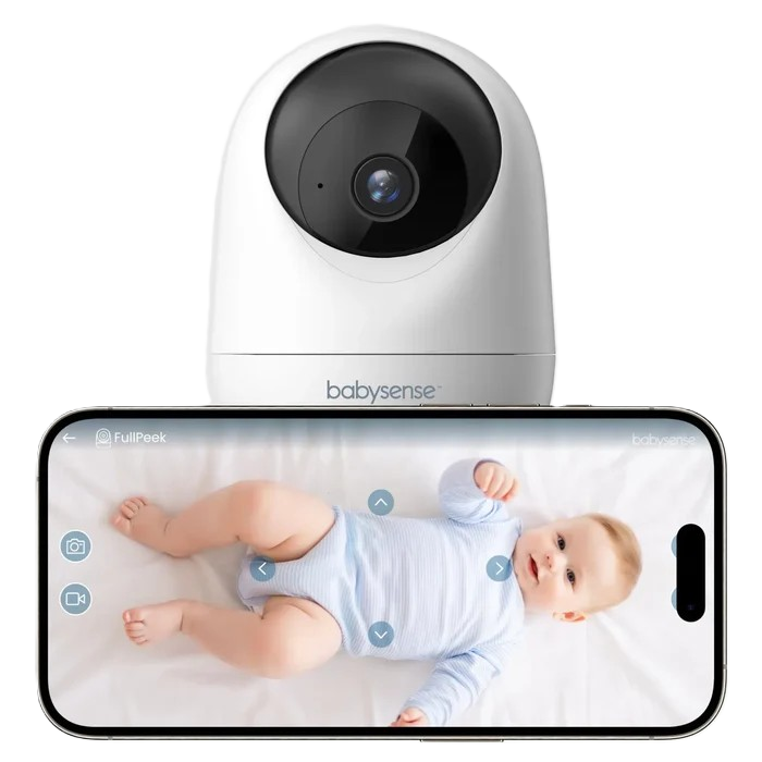 a baby laying on top of a bed next to a camera