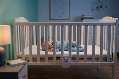 a baby sleeping in a crib with a breathing monitor attached to the front
