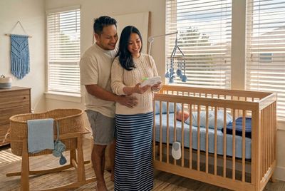 a man and woman standing next to a baby crib