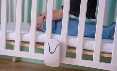 a baby laying in a crib next to a baby monitor