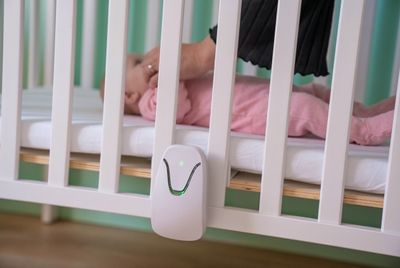 a baby laying in a crib next to a baby monitor