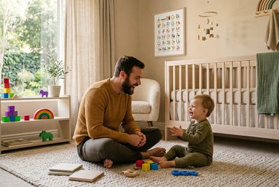a man sitting on the floor playing with a toddler