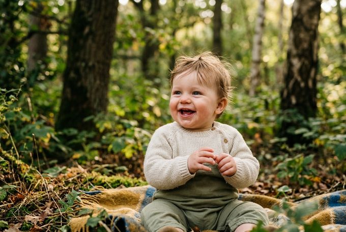 a baby sitting on a blanket in the woods