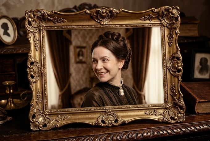 a woman is smiling in front of a mirror