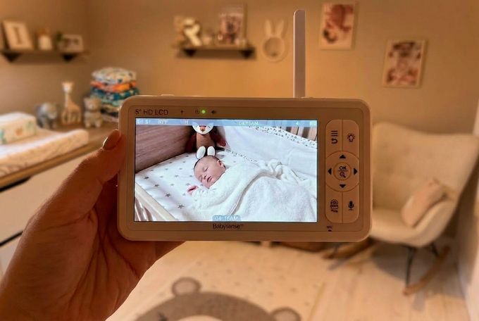 a person holding up a video baby monitor in a nursery