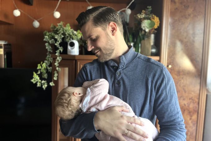 A father carrying his sleeping baby.