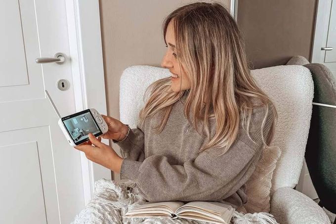 A mother looking at her baby monitor to check on her child.