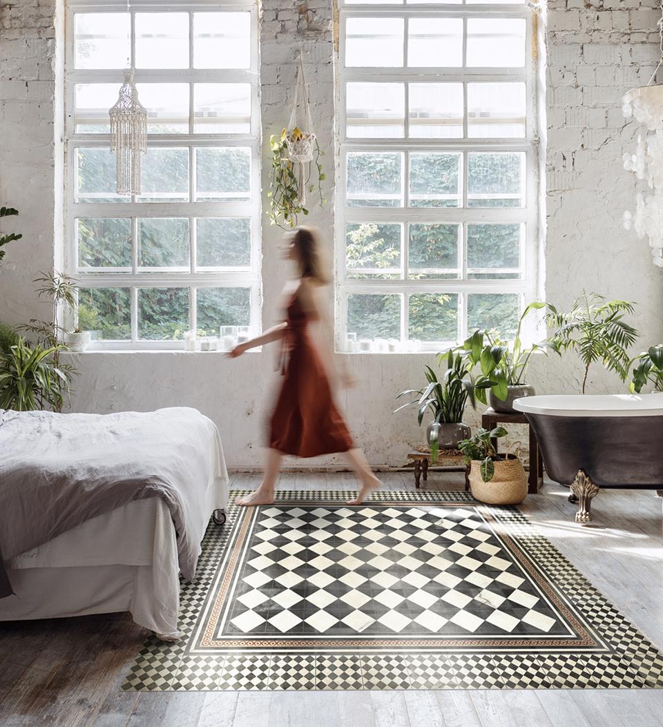 Woman walking on a black and white checker board patterned rug under a bed 