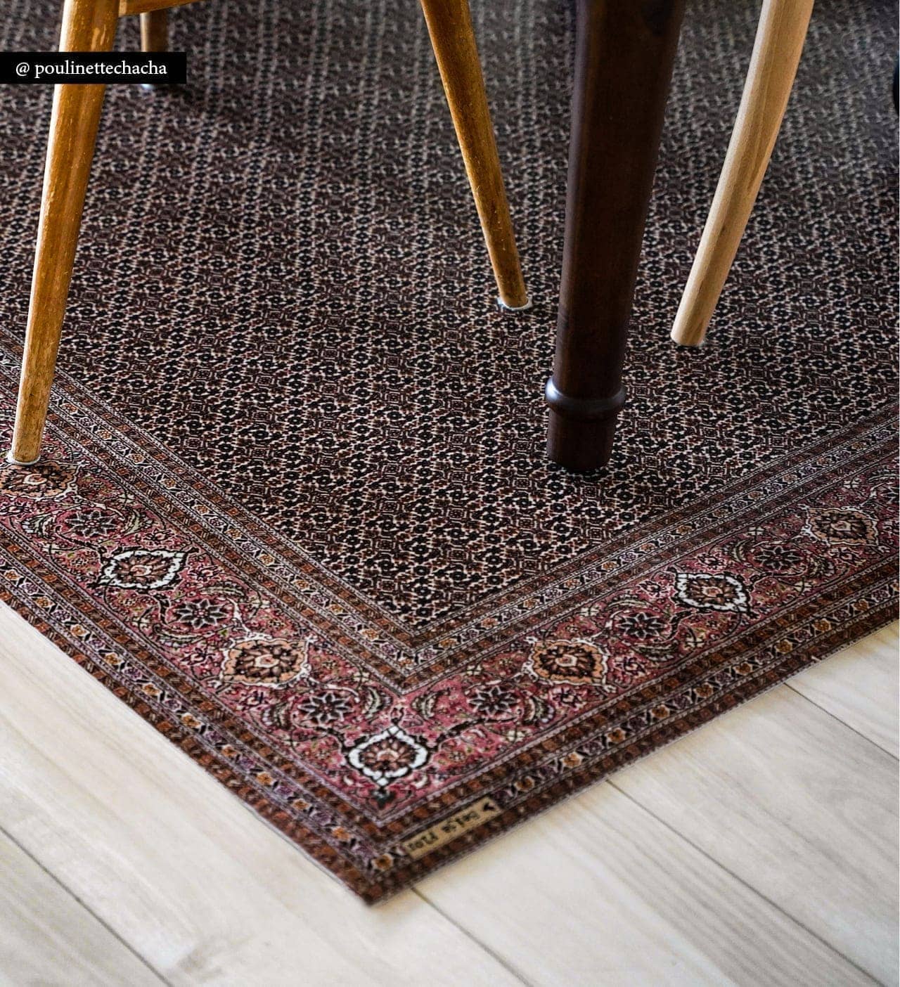 The corner of a Persian rug placed under a kitchen table with chair legs on top of it