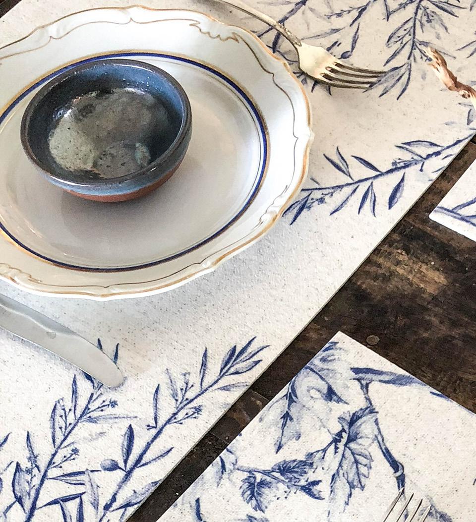 A placemat with deep blue water color illustrations placed under a tea set 