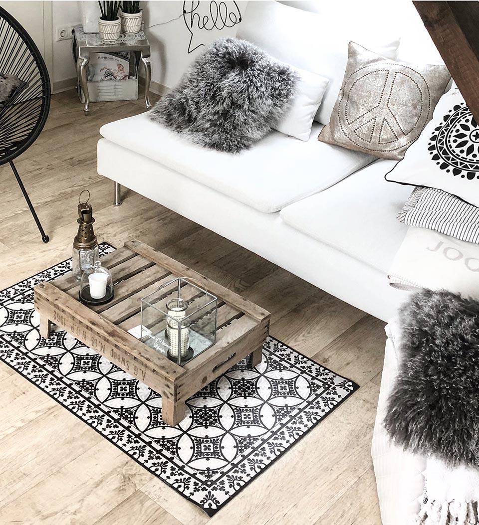 A small black and white patterned rug under a rectangular coffee table on a living room floor