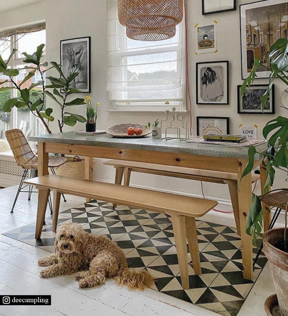 A modern dining room with a black and white triangle-patterned rug under the table with a dog sitting on it