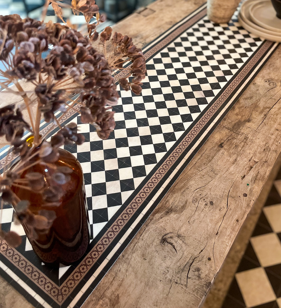 A checker board pattern vinyl table runner spread over a wooden table with plates
